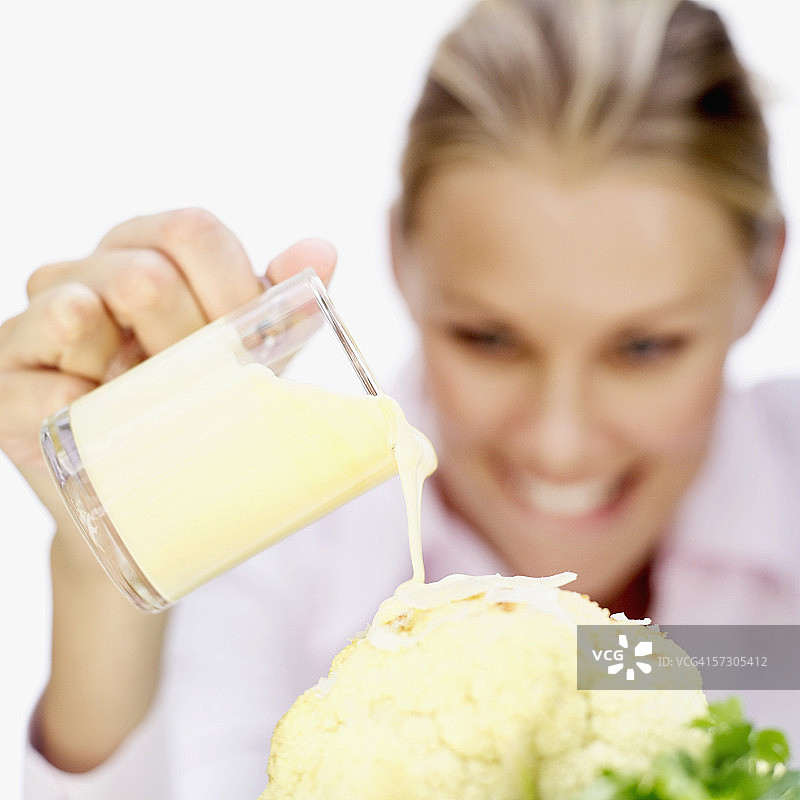年轻女人在花椰菜上倒酱汁图片素材