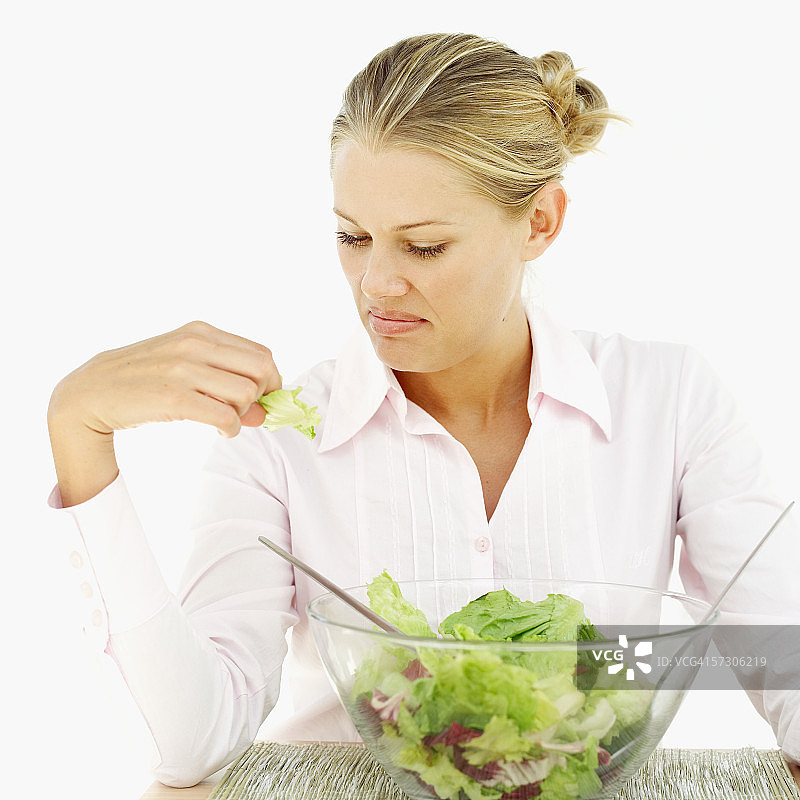 年轻女性皱着眉头看着手中的生菜图片素材
