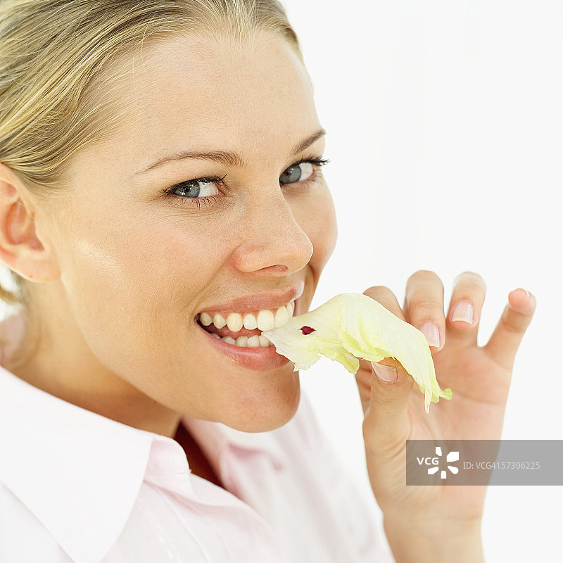 年轻女子将生菜放入口中的特写镜头图片素材