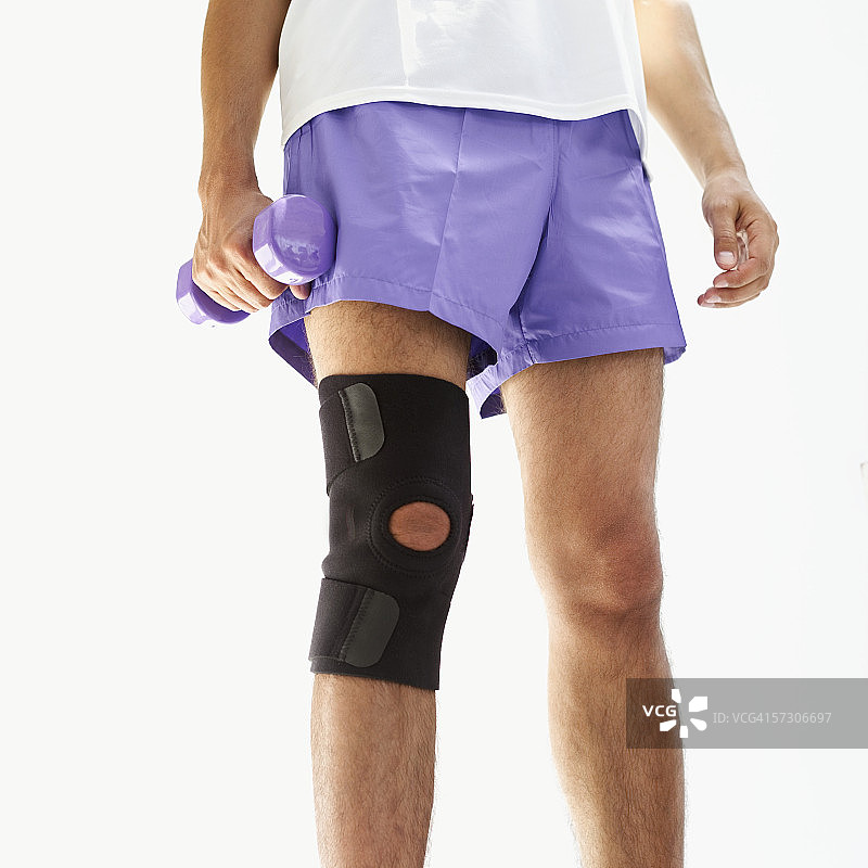 男人佩戴护膝举哑铃的特写图片素材