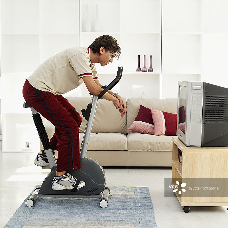 一个年轻男人坐在健身自行车上的侧面轮廓图片素材