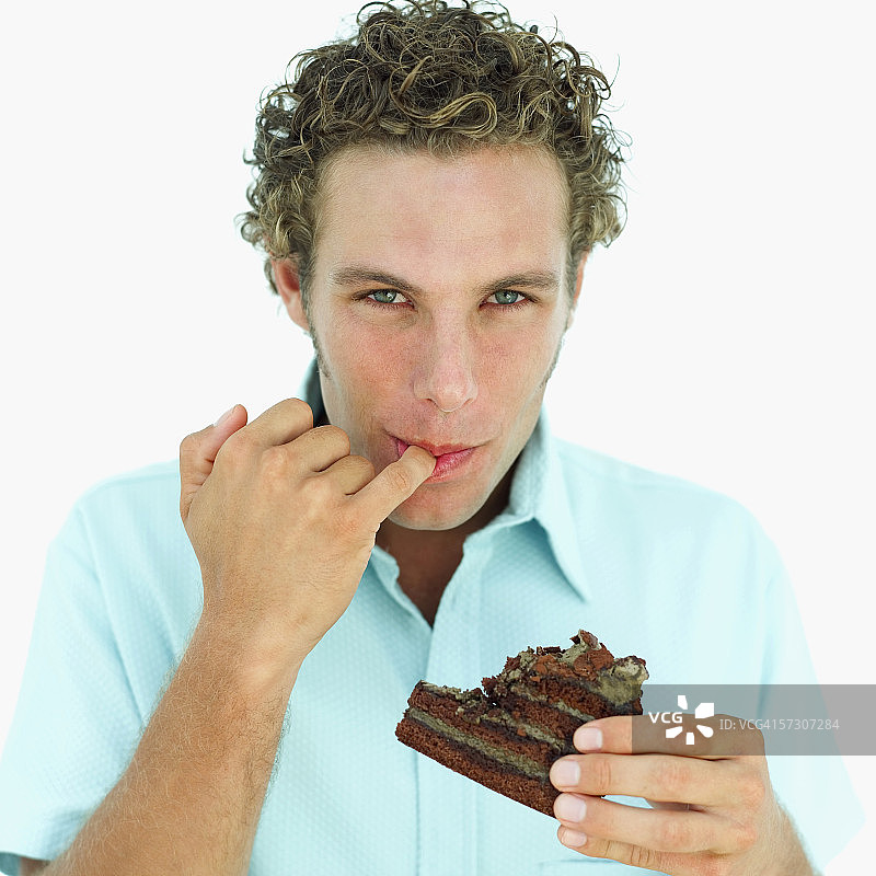 年轻人舔手指上的巧克力图片素材