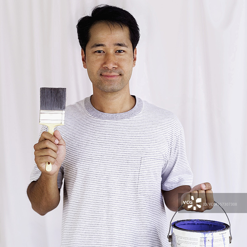 年轻男人手持画笔和油漆桶的肖像图片素材