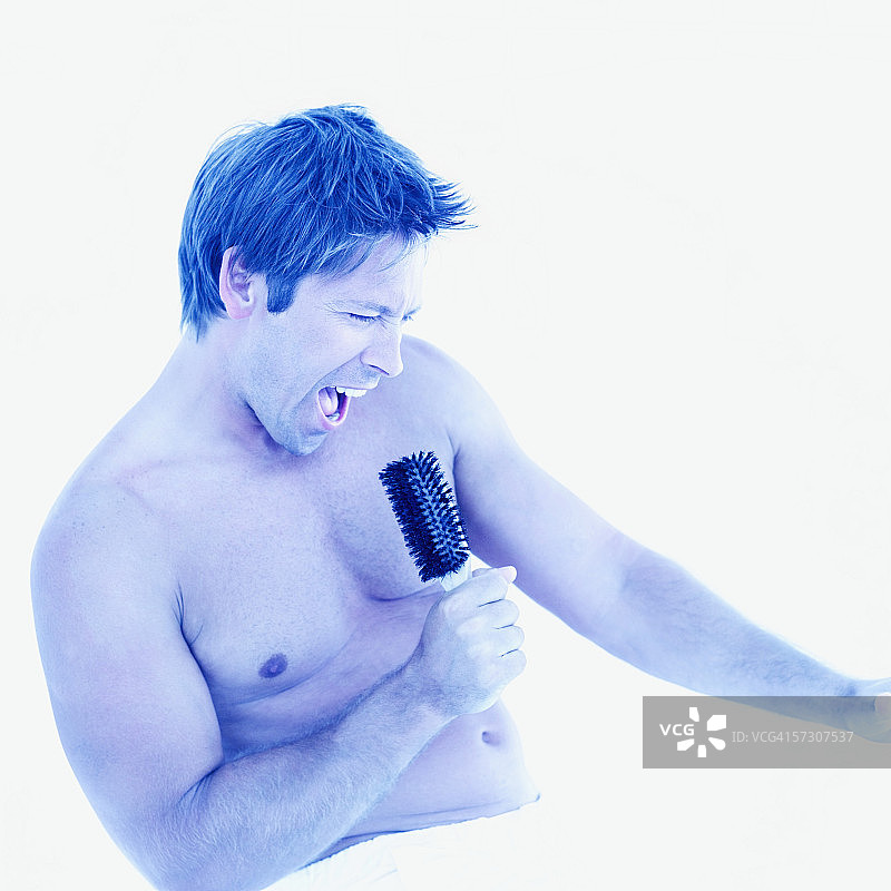 腰间围着毛巾、对着发刷唱歌的年轻男人图片素材