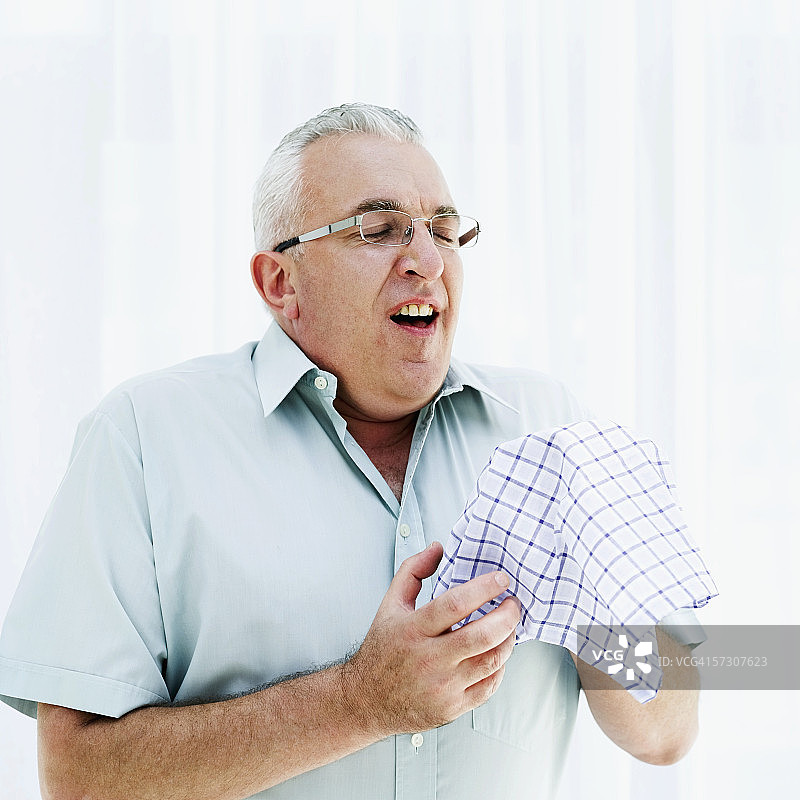 一位拿着手帕准备打喷嚏的老年男人图片素材