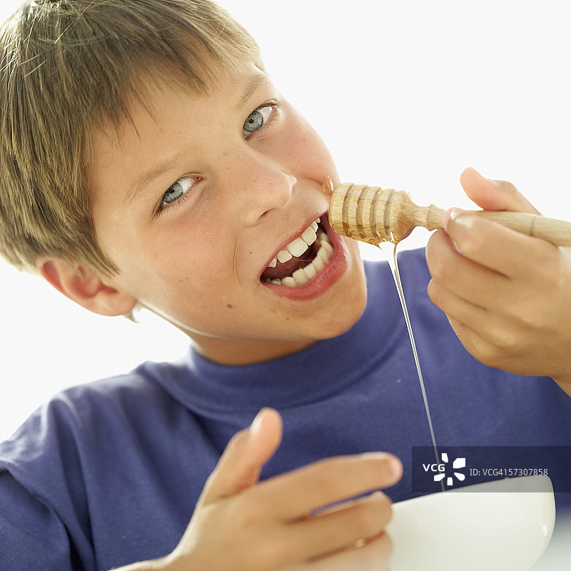 手持蜂蜜勺的年轻男孩肖像图片素材