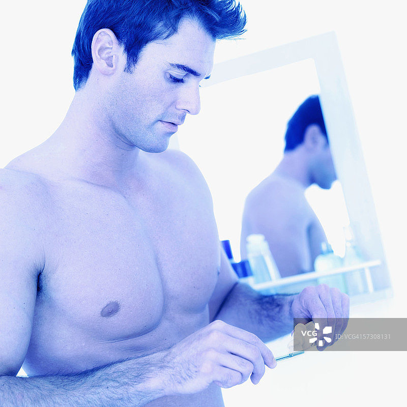 将牙膏挤到牙刷上的年轻男子侧面像图片素材