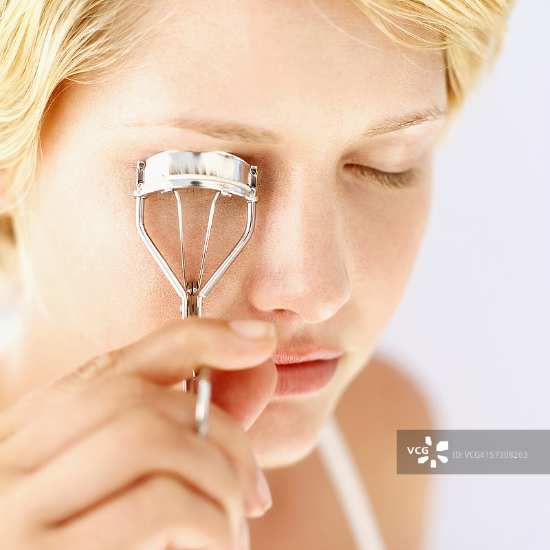 年轻女人使用睫毛夹特写图片素材