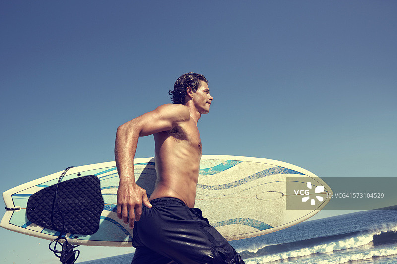 白人男子在海滩上扛着冲浪板图片素材