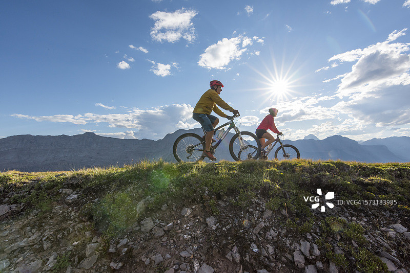 山地自行车手在山脊上骑行，日出图片素材