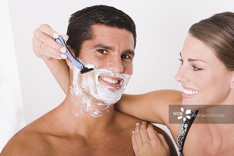 年轻女子为中年男子剃须特写图片素材