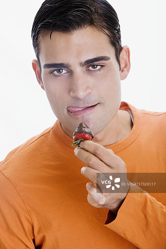 嘴前拿着巧克力草莓的中年男子肖像图片素材