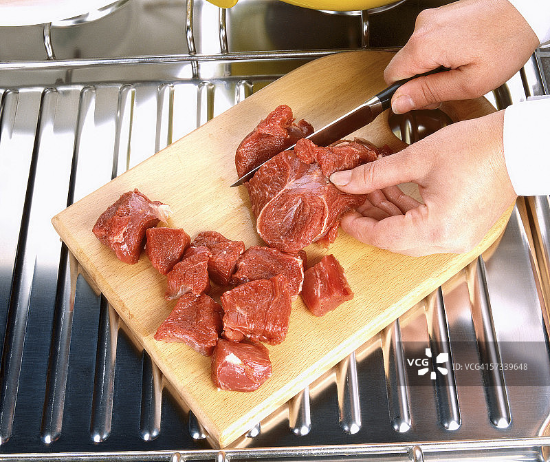 特写：在木板上切割红肉的手图片素材