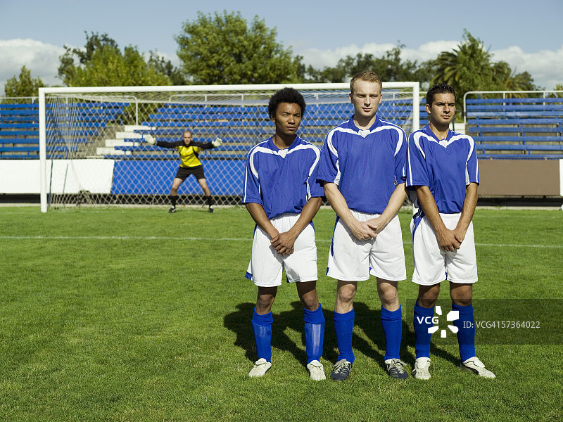 三名足球运动员防守任意球图片素材