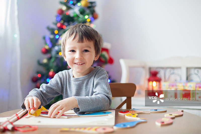 在家制作木制拼图的可爱小男孩图片素材