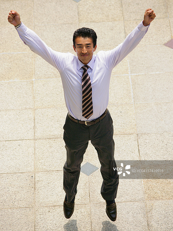 举起双臂跳跃的商人的俯视角度图片素材