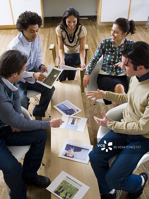 两位年轻女性和三位中年男子看照片的俯视图图片素材