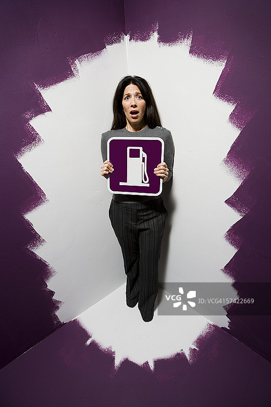 中年妇女拿着燃油泵标牌的肖像图片素材