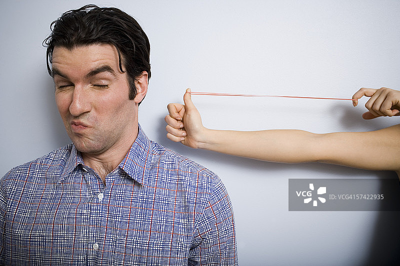 女人用橡皮筋瞄准年轻男人的手部特写图片素材