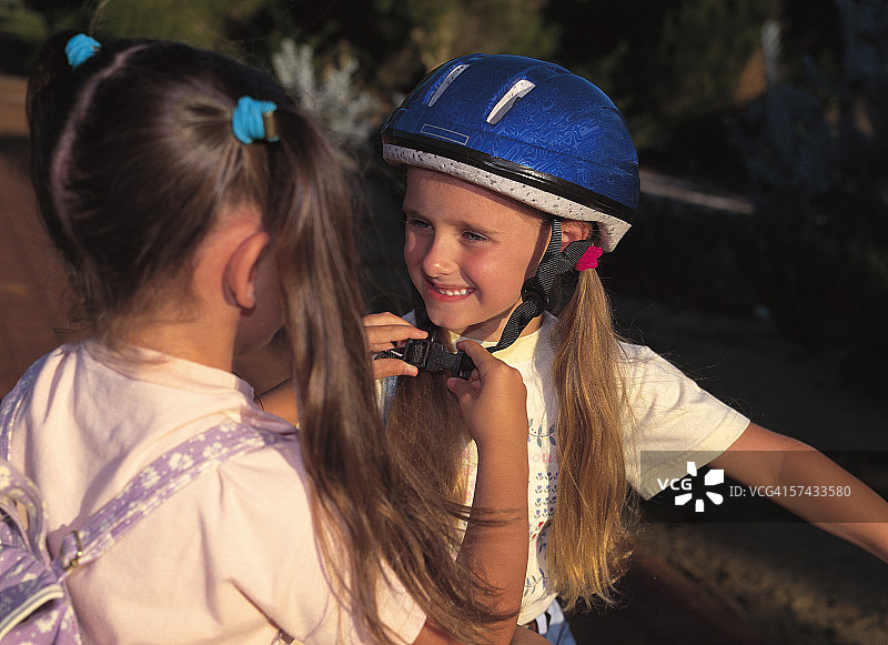 年轻女孩帮助她的妹妹戴上安全头盔图片素材