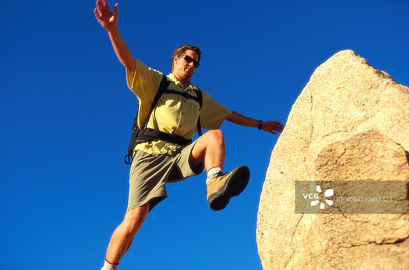 男子跳跃跨越岩石（低角度仰视）图片素材