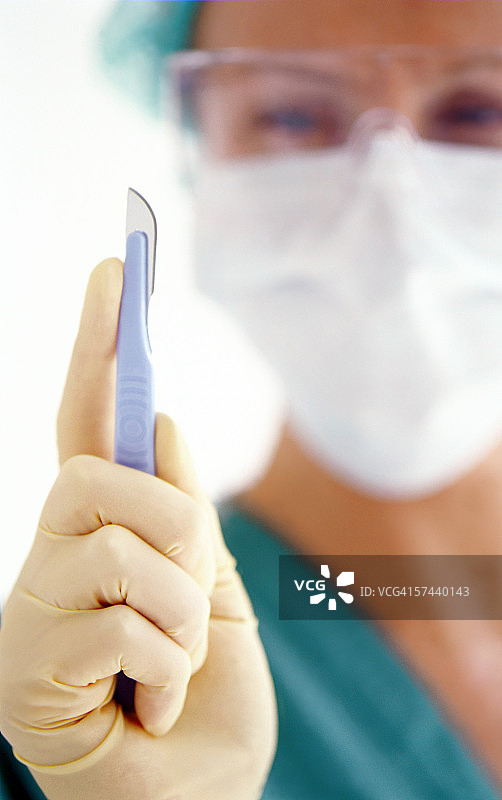医生戴着乳胶手套，拿着手术刀图片素材