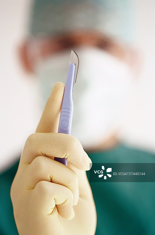 医生戴着乳胶手套，拿着手术刀图片素材