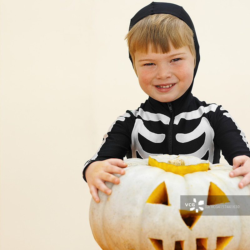 穿着骷髅服装和拿着万圣节南瓜的男孩（5-6岁）图片素材