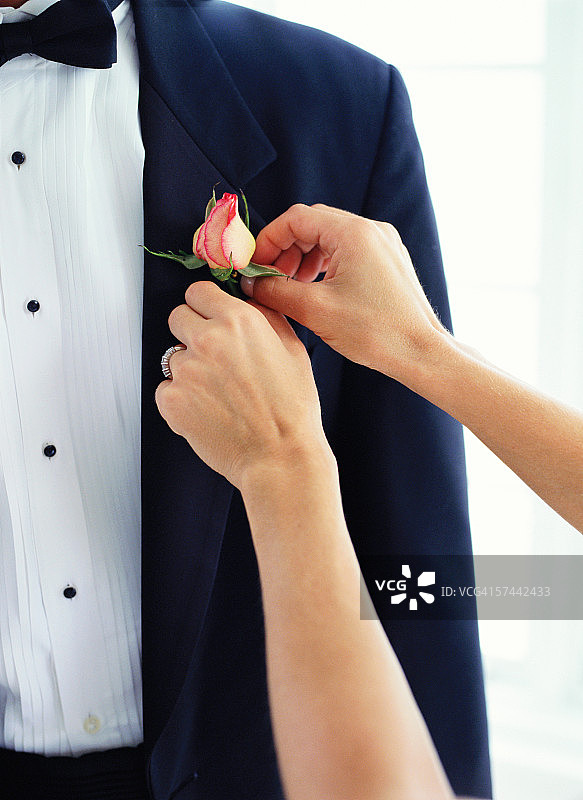 女人在男士礼服上别胸花图片素材