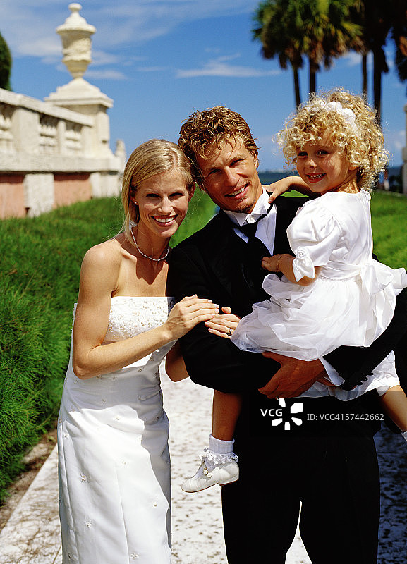 新郎抱着女孩（6-8岁）与新娘合影图片素材