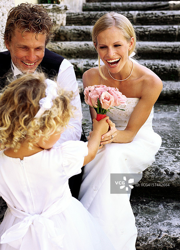 一个(6-8岁)女孩给新娘送玫瑰花束的背影图片素材