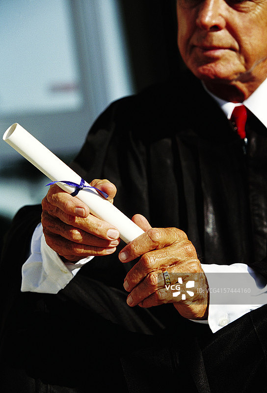 一位老人拿着文凭的特写图片素材