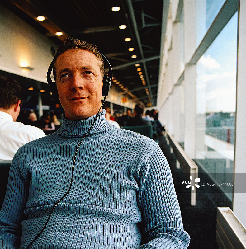 在机场戴耳机听音乐的男子特写图片素材