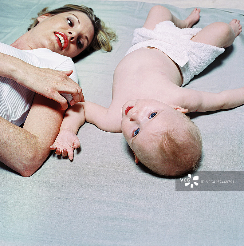 年轻女人和宝宝（12-18个月大）一起躺在床上图片素材