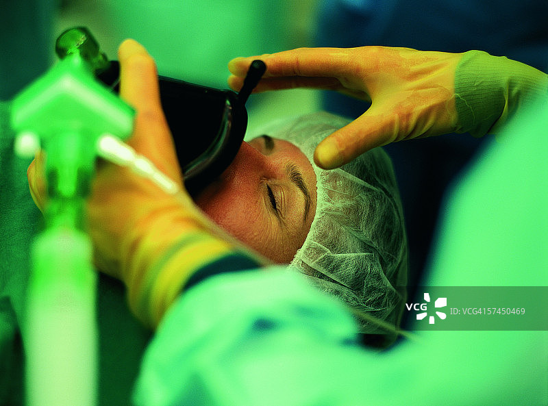 穿手术服的医务人员手持氧气面罩，罩在病人的嘴上图片素材