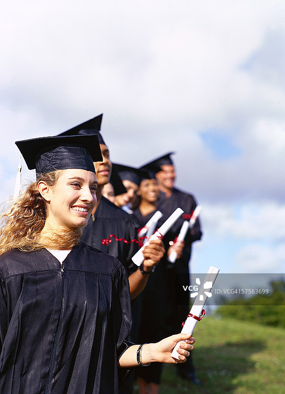 一群年轻毕业生手持学位证书站成一排的肖像图片素材