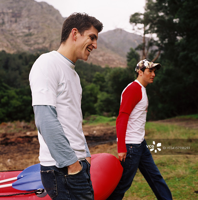 两个年轻人抬着充气筏的侧面轮廓图片素材