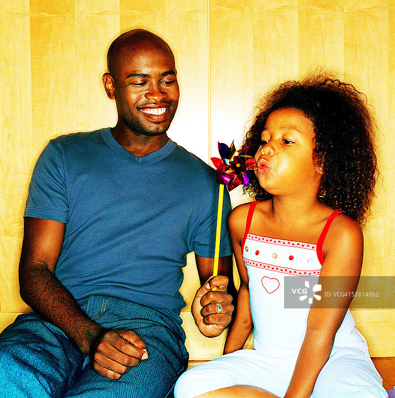 年轻男人和一个小女孩（8-10岁）一起吹风车图片素材