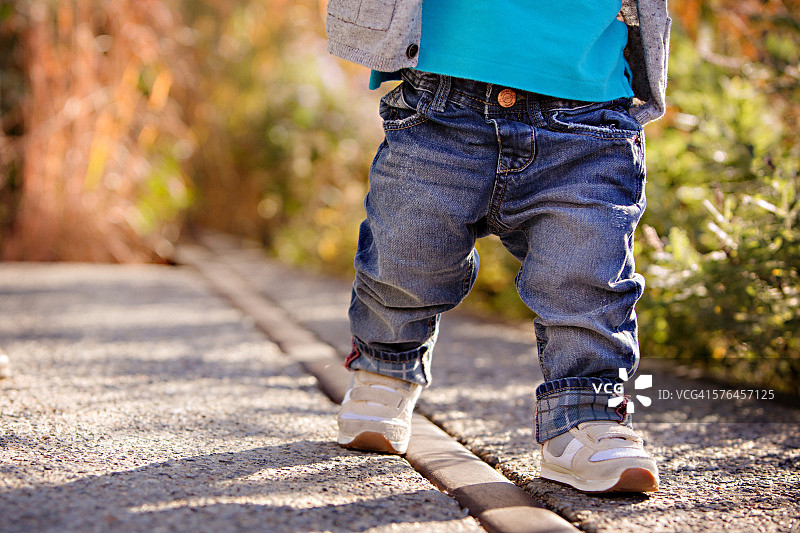 穿着牛仔裤的幼儿男孩在户外迈出第一步图片素材