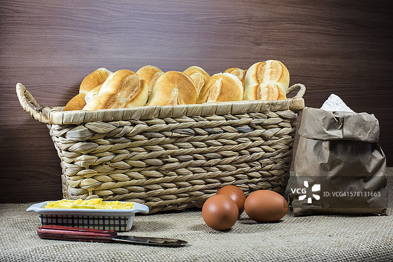 篮子里的面包、小麦、黄油和鸡蛋静物图片素材