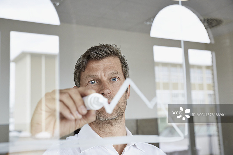 商人在办公室的玻璃上绘制图表图片素材