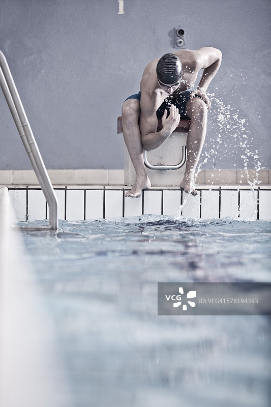 在室内游泳池坐在起跳台上的游泳者图片素材