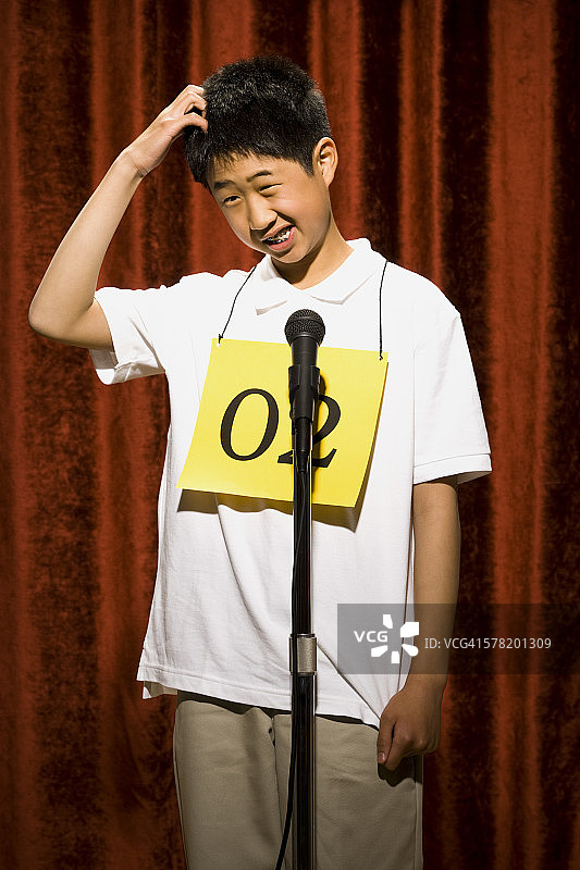 男孩在麦克风前挠头图片素材