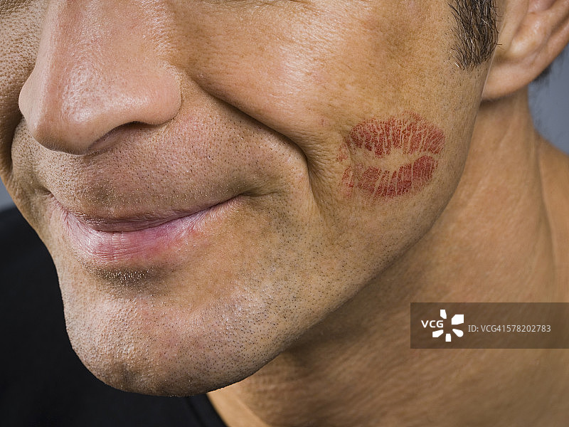 特写：男人微笑，脸颊上有唇印图片素材