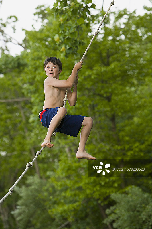 男孩荡绳子的侧面照图片素材