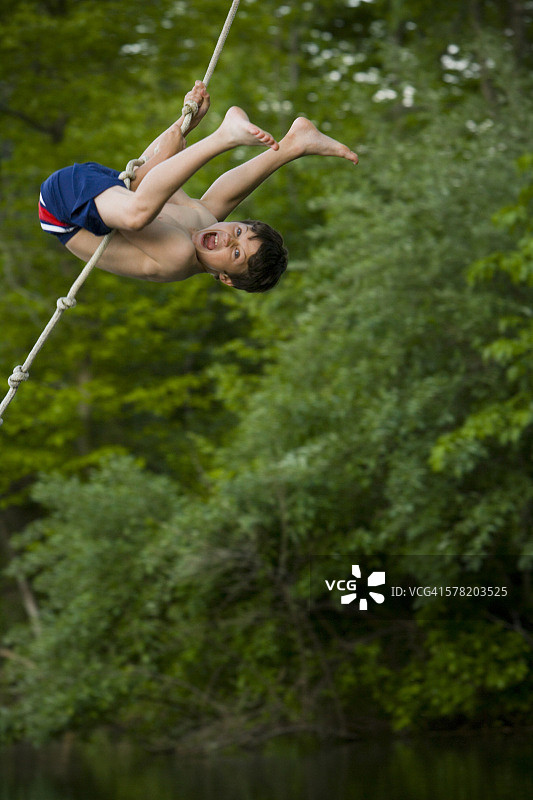男孩荡绳子的侧面照图片素材