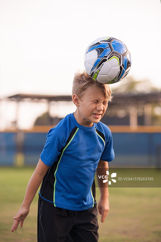 在训练场上用头顶足球的闭眼男孩图片素材