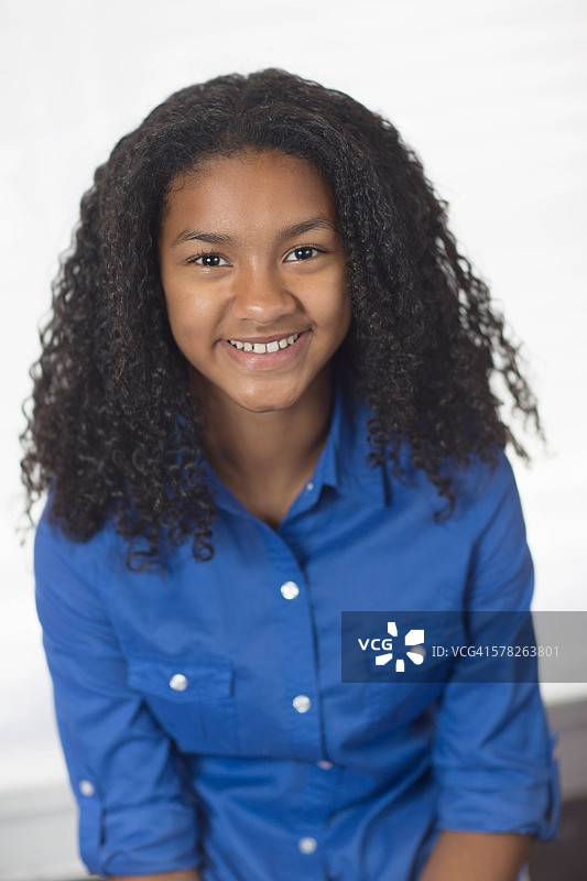 看着镜头的黑色卷发微笑女孩肖像图片素材