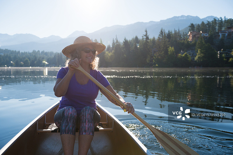 在原始湖上划独木舟的老年妇女图片素材