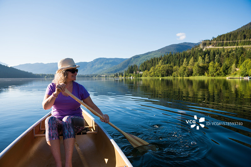 在原始湖上划独木舟的老年妇女图片素材